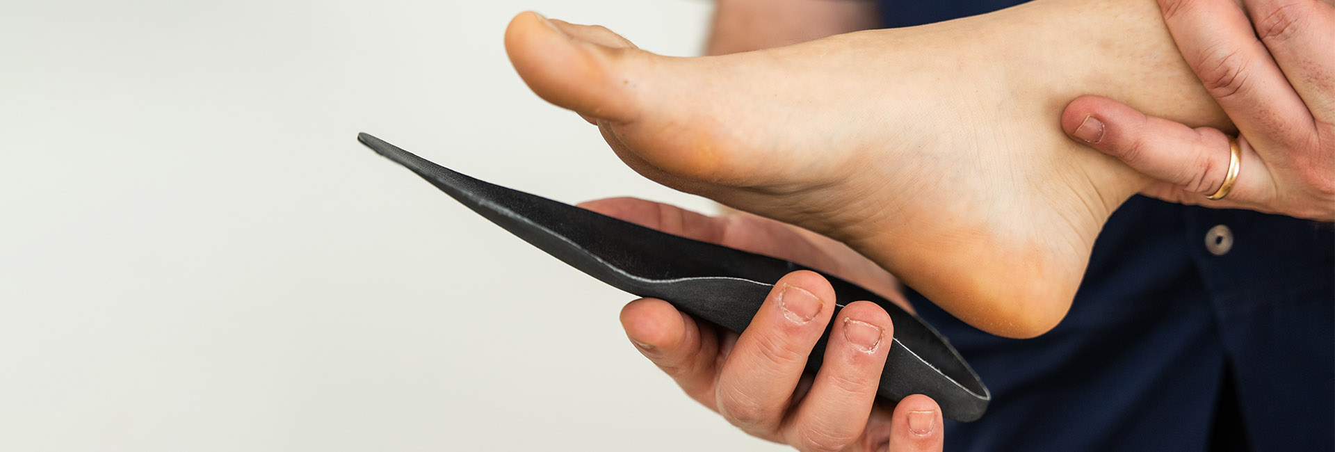 Podiatrist holding a custom foot orthotic beneath a patient's foot